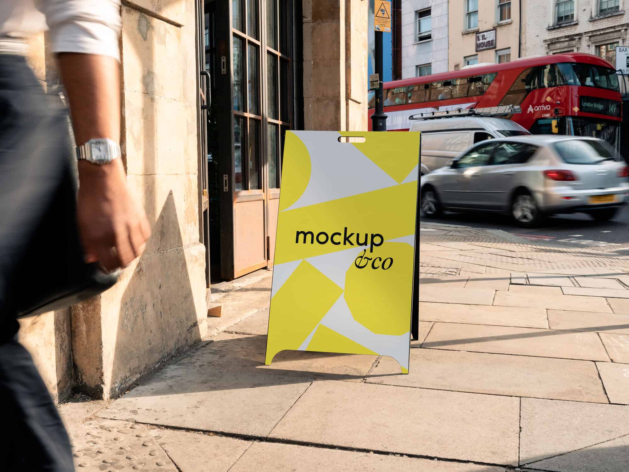 Free customisable A-frame mockup with a London backdrop, ideal for presenting branding, artwork, or promotional materials in a urban environment.