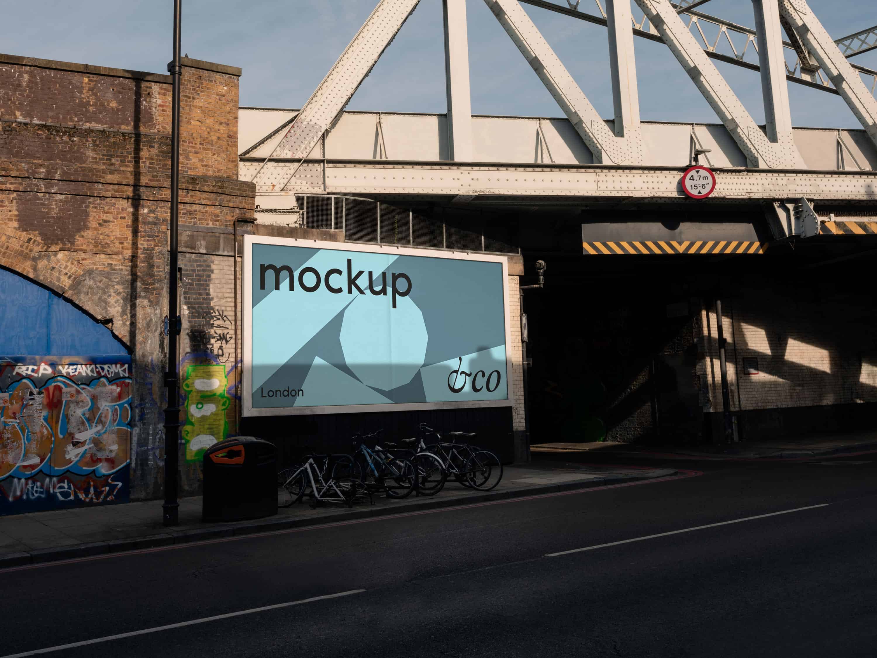 Premium London billboard mockup shot in East London under a railway with dramatic evening lighting and graffiti, featuring a fully editable billboard for showcasing urban designs in an edgy, metropolitan setting.