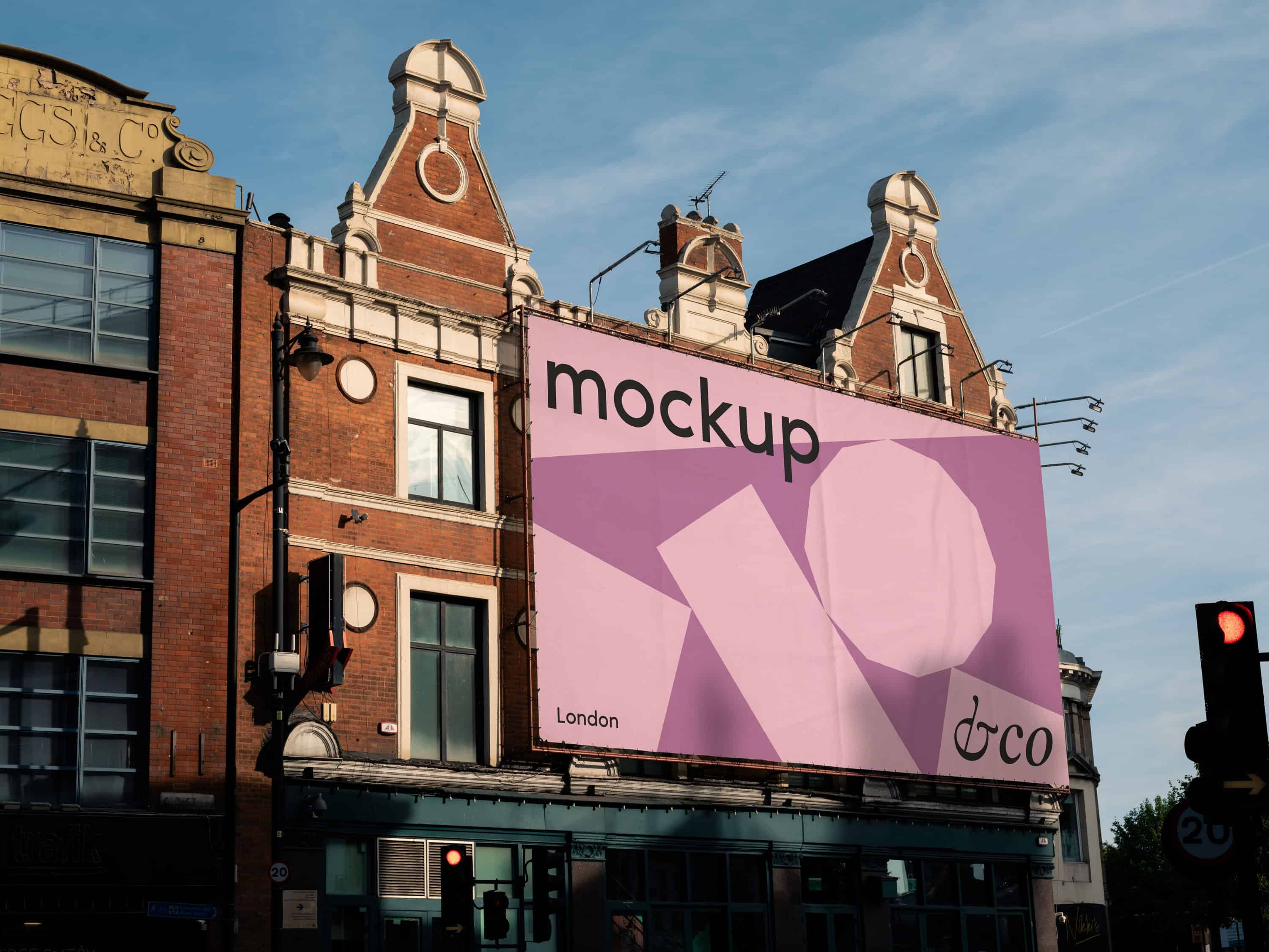 Premium London billboard mockup on a brick building, next to traffic lights, with the sky in the background. Fully editable for showcasing designs and branding in a classic London urban setting.