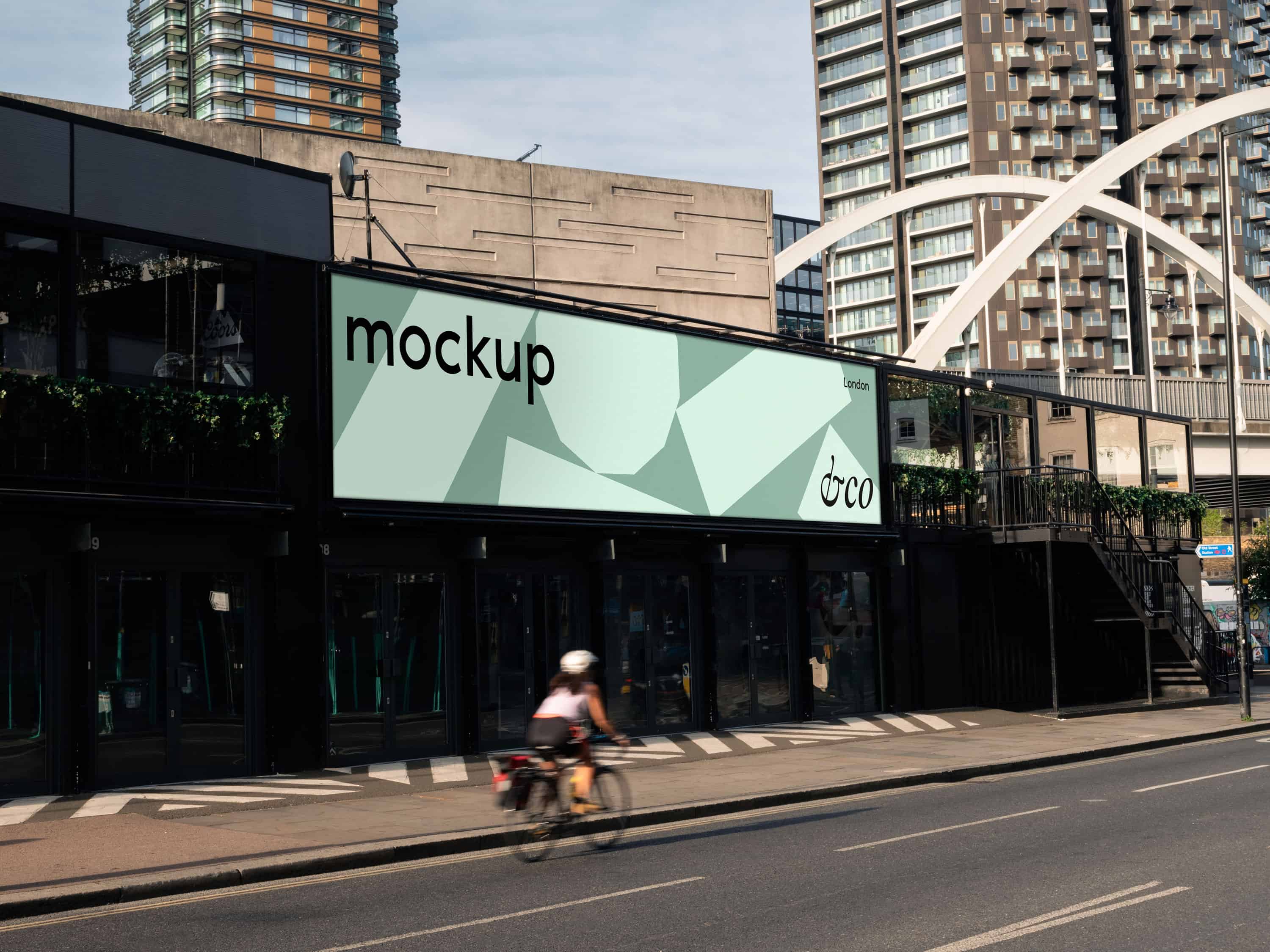 Premium London billboard mockup with a bike in a natural outdoor setting, featuring a fully editable background for showcasing designs in a fresh, active environment.